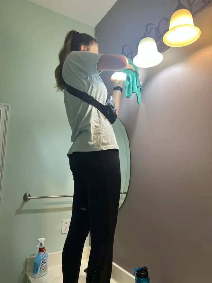 Simplicity by Becky team member hand-wiping a bathroom light fixture
